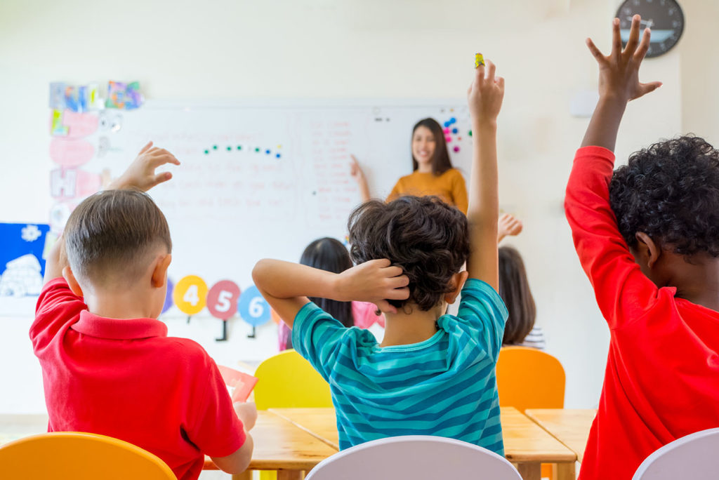 Children raising their hands in a catholic kindergarten class