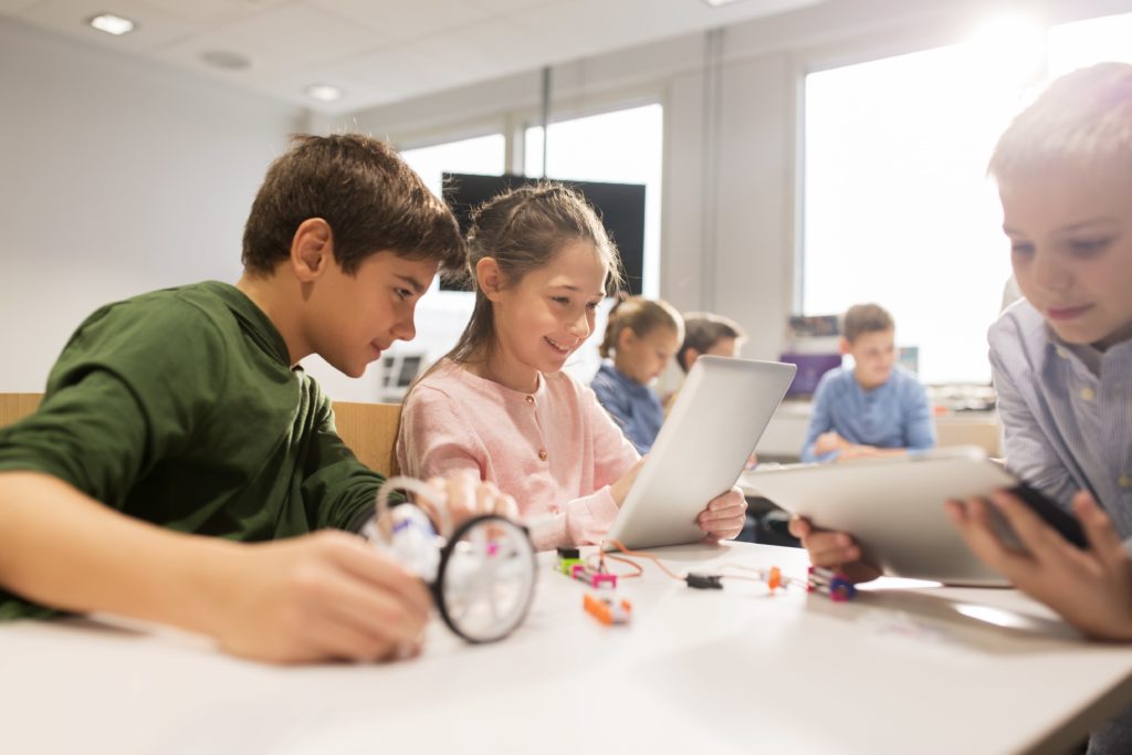 Kids working on tablet to program robot