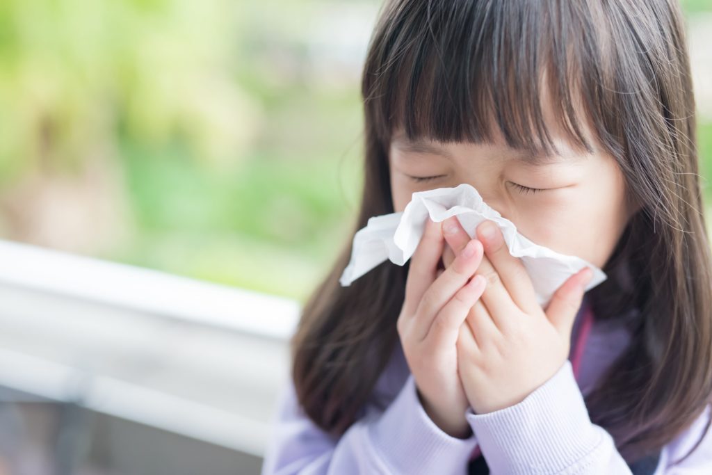 Little girl with bangs blowing nose