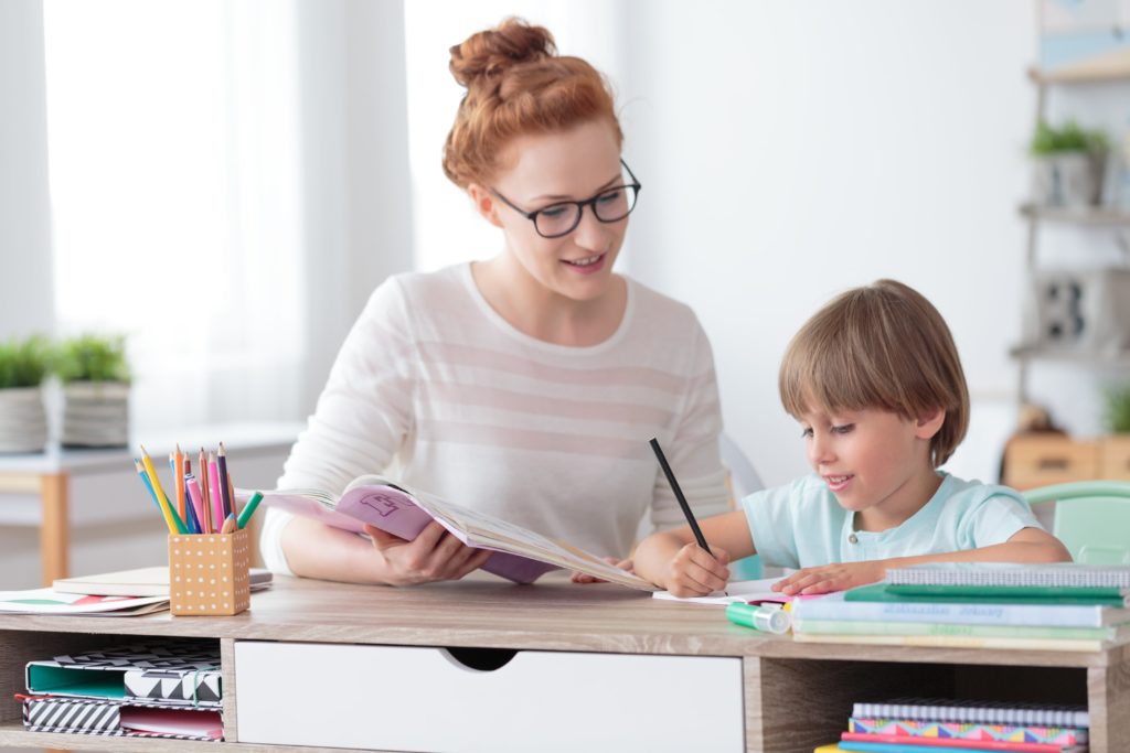 Mom with glasses helping son with schoolwork