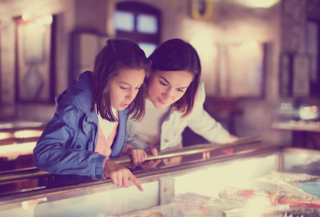 Mother and daughter examining item at museum