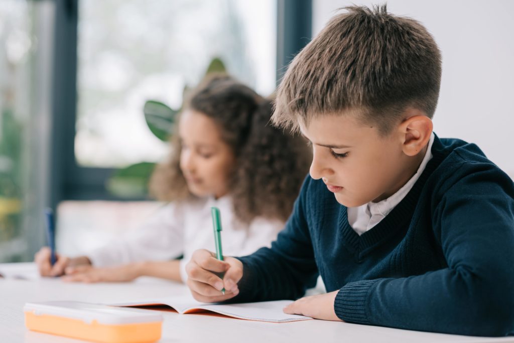 Young boy doing his school work in class