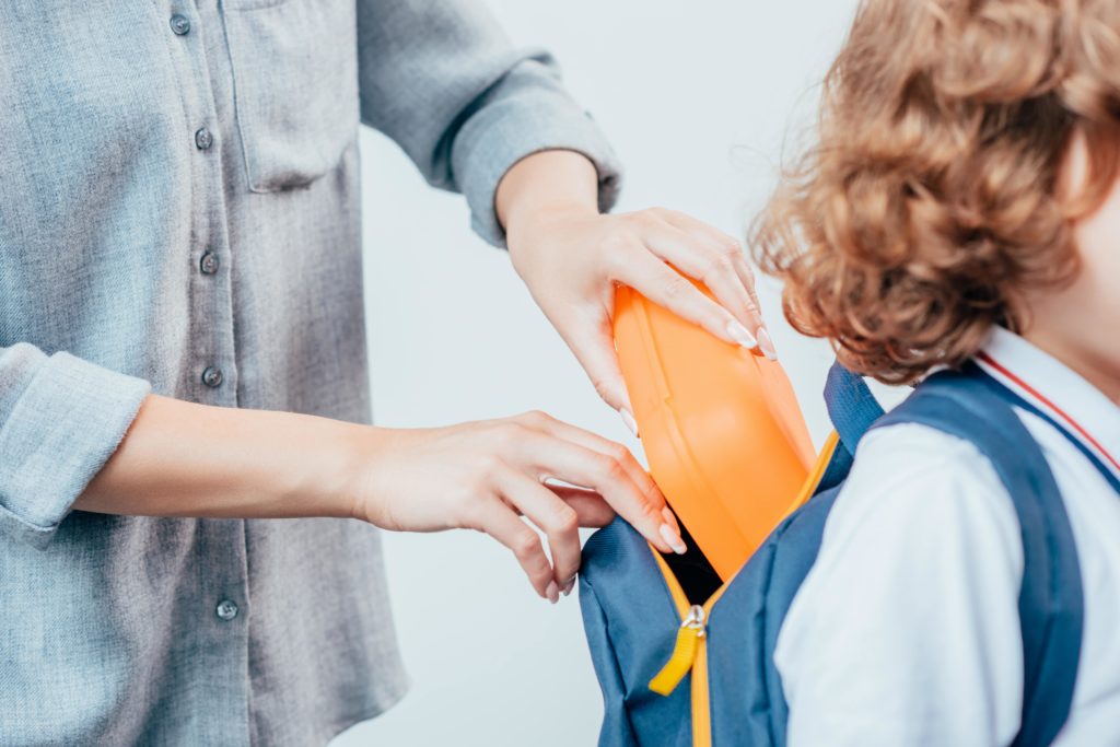 Mom putting lunch in student’s backpack