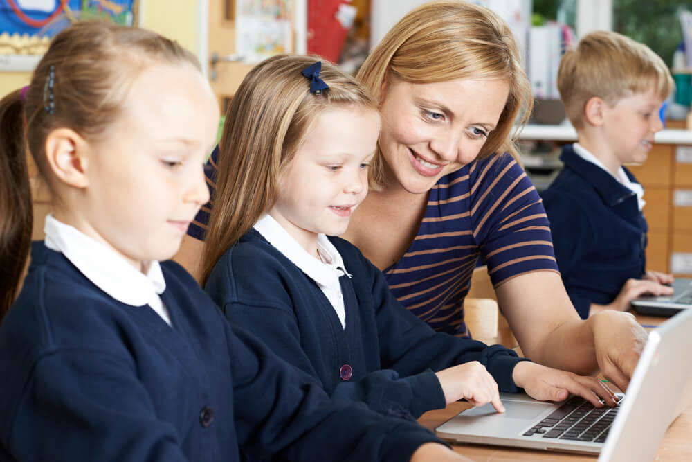 Teacher working with students on laptops