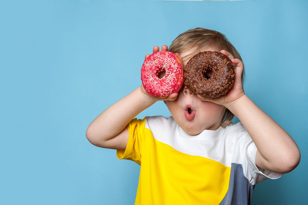 Happy child holding donuts to his eyes