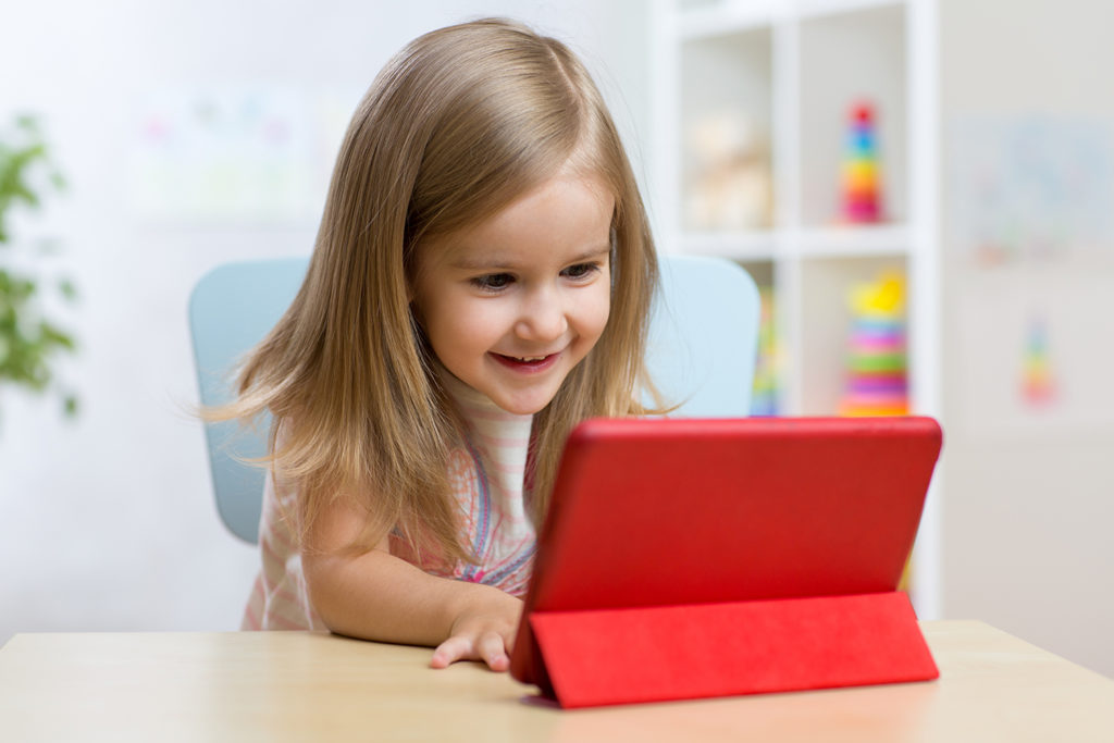 Little girl using a tablet at her desk