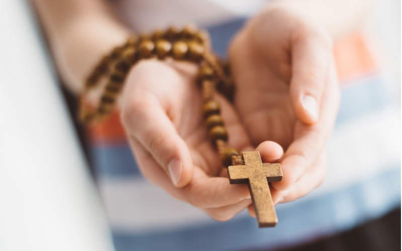 closeup of hands holding a rosary