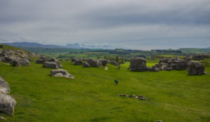 image of green grass with large boulders against a cloudy sky