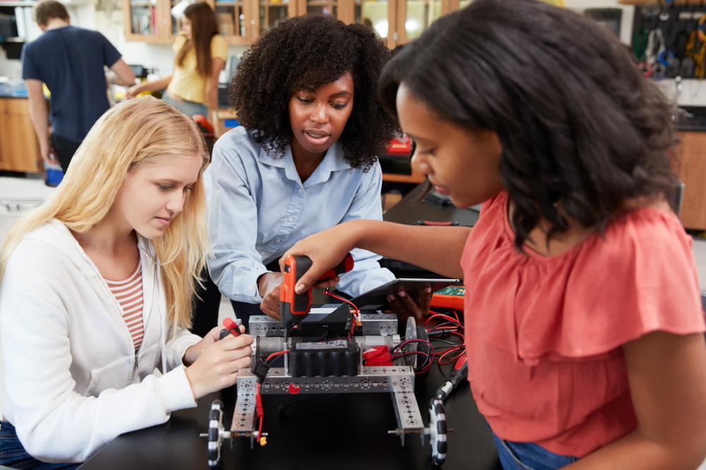 Teacher with robot teaching two middle school girls
