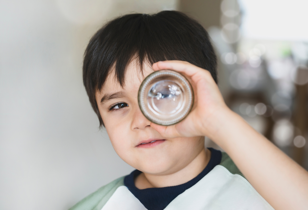 Boy looking through a glass bottle