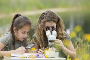 Young Girls Looking at Plants Under a Microscope