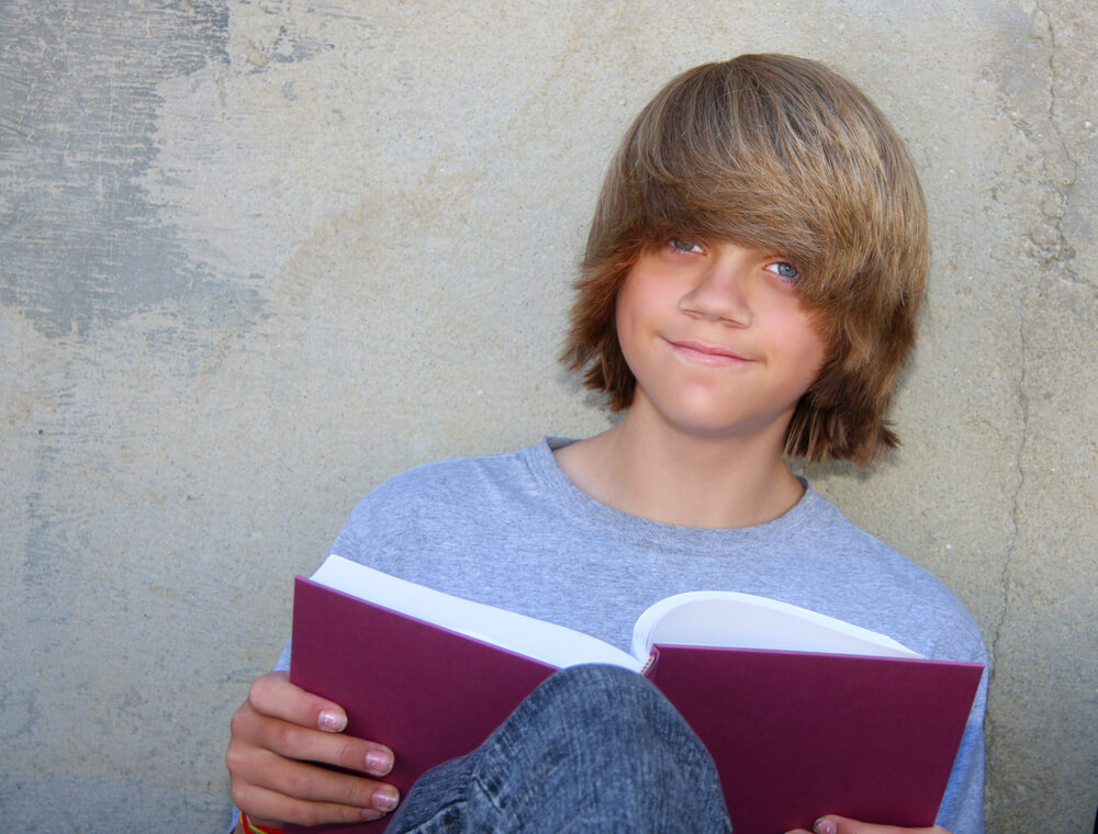 Middleschool student reading a book with long brown hair