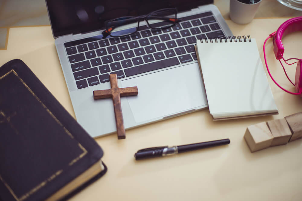 Bible, cross, and laptop on desk