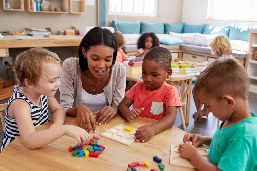 Preschoolers and teacher playing with colored shapes