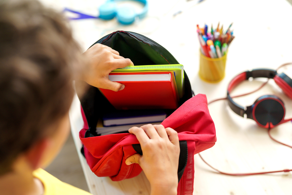 A student placing books in a backpack