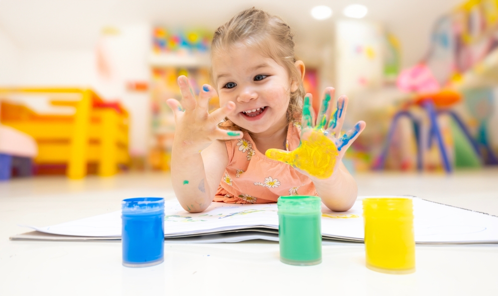 Cute preschooler with paint on her hands