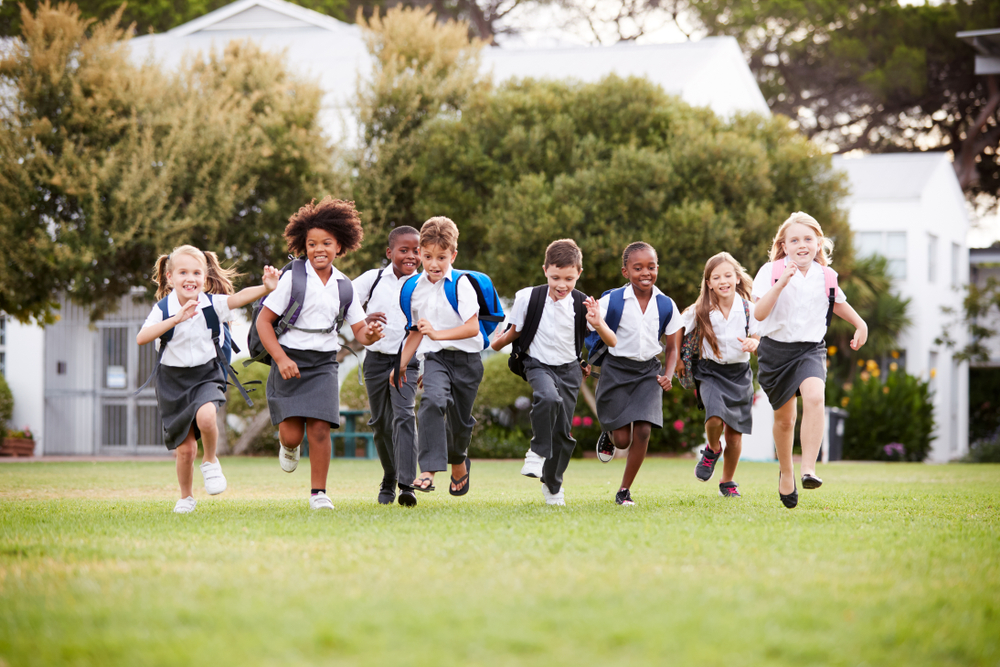 Elementary-aged private school students running across a lawn