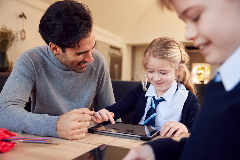 Father helping children with homework on a tablet